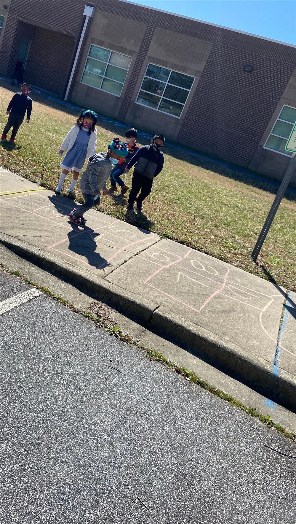 students playing with chalk on sidewalk